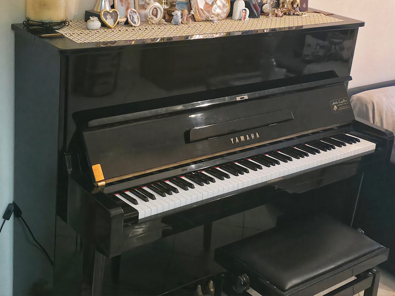 Pianoforte verticale nero chiuso con luce naturale e artificiale che illumina la superficie